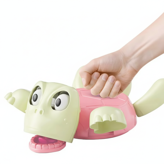 Hand holding a green and pink plastic turtle toy with large eyes and open mouth