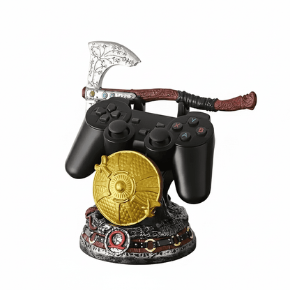 Suporte para controle de videogame com tema de God of War, apresentando machado, escudo dourado e cinto de couro sobre base de pedra.